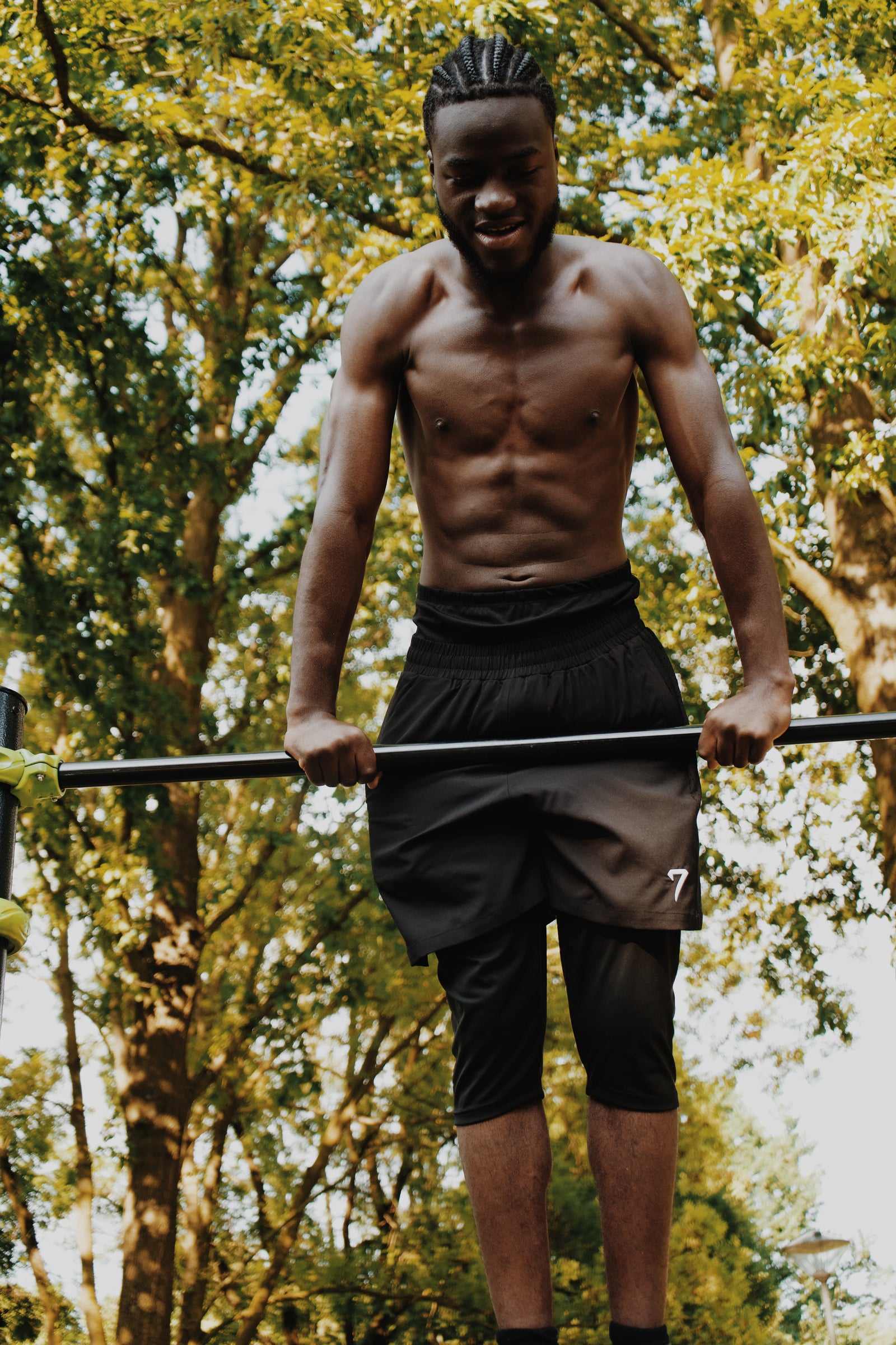 Athlete at the top of a pull-up bar wearing the 7ayaa Performance Shorts, the legging layer keeping the leg covered below the knee
