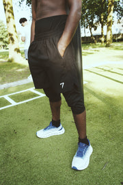 Rear three-quarter view of the shorts with a hand in the side pocket, showing the perforated ventilation panel and the vented hem