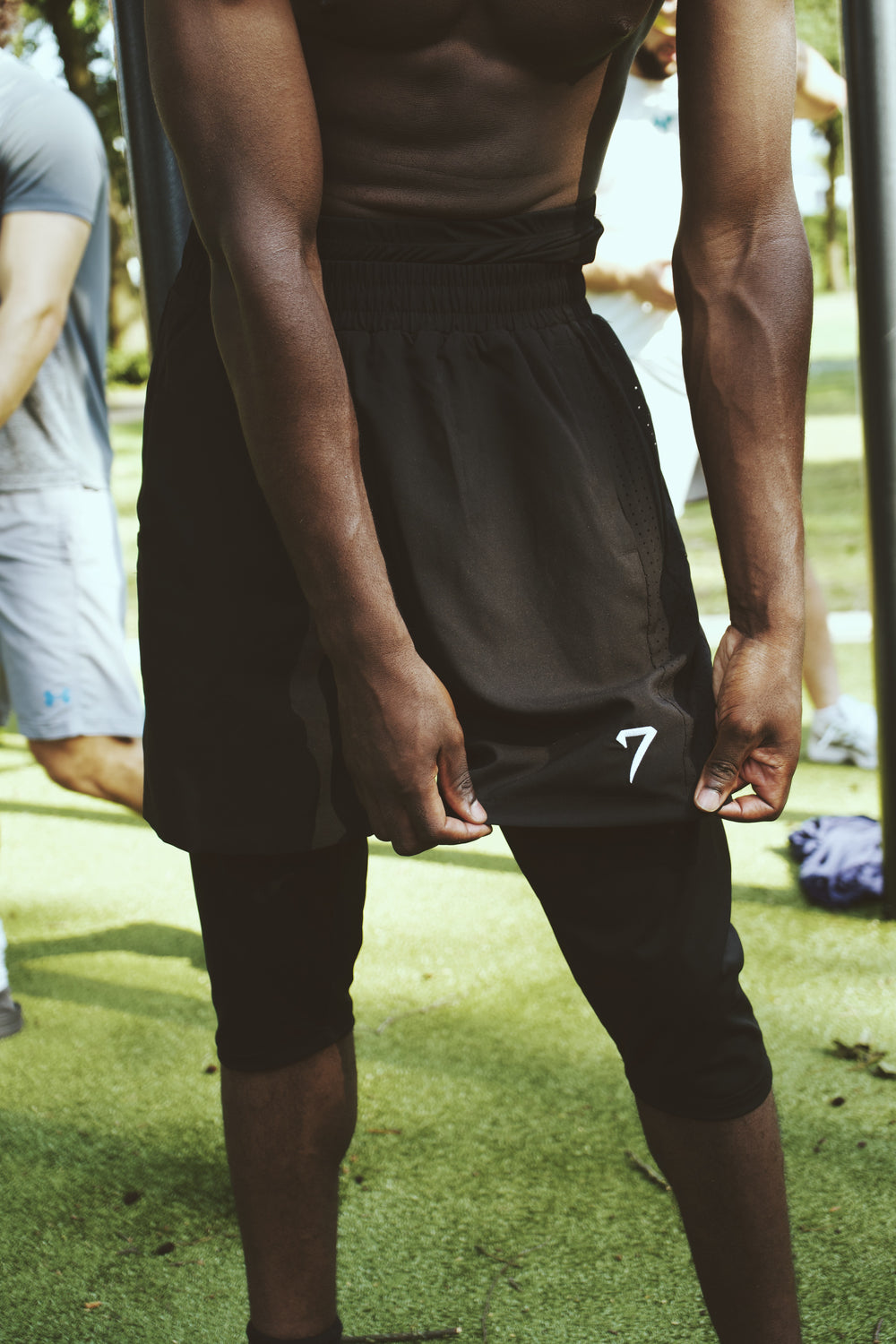 Close view of the shorts worn over the legging layer, showing full coverage past the knee and the embroidered 7 mark