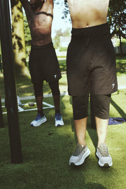 Two athletes photographed from the waist down, showing the shorts and legging layer from the front and the side
