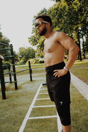 Side profile of the 7ayaa Performance Shorts worn outdoors, showing the drawcord waistband and the length of the legging layer